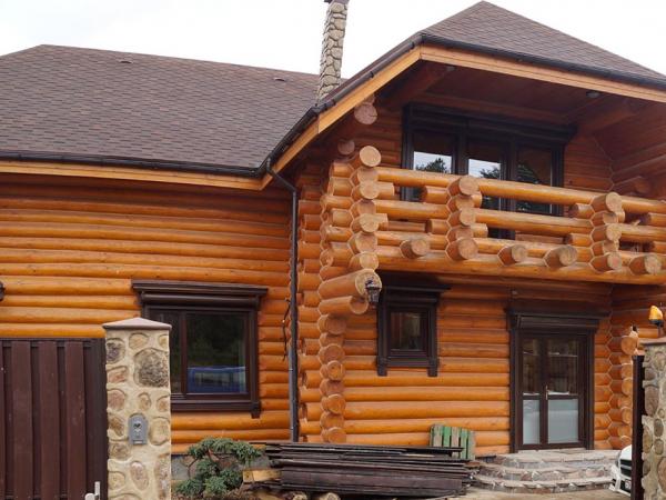 Деревянные окна в коттедже из бревна с наличниками вид на балкон